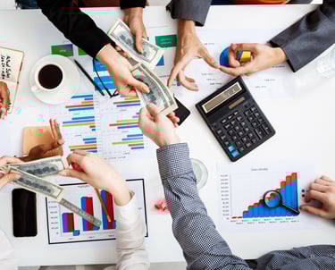 a group of people sitting around a table with money