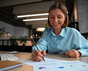 a woman in a blue shirt is smiling and holding a pen