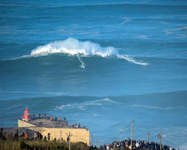 a large wave coming in to shore with people standing on the beach