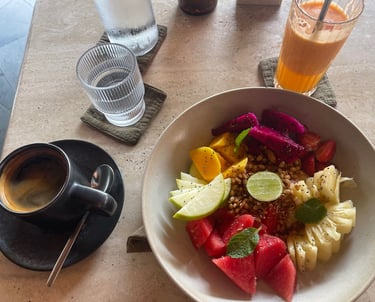 Petit-déjeuner chez Muda à Canggu : assiette de fruits colorés, jus de fruits frais et café 