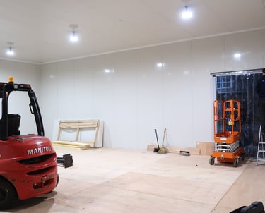Interior of a spacious freezer warehouse showing both a forklift and scissor lift, illustrating the 