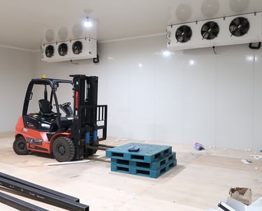 Wide view of a giant commercial freezer room with a forklift inside, highlighting the massive scale 