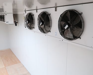 Two large industrial evaporators mounted on the ceiling of a giant commercial freezer room for cold 