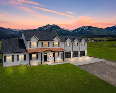 a large house with a large lawn and mountains in the background