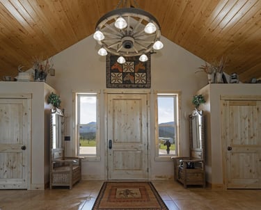 Custom home by Saddle Horn with stone tiles and wood ceilings. Front door.