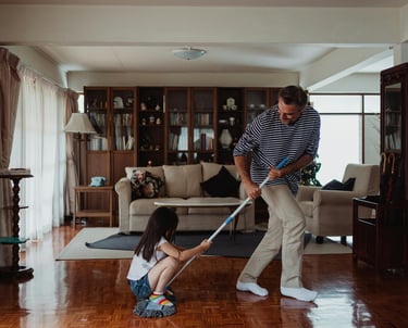 Father playing with daughter on wood floor in custom house
