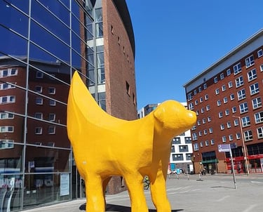 a yellow dog statue of a dog in front of a building