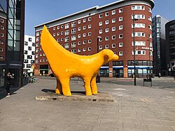 a yellow dog statue of a dog in a city