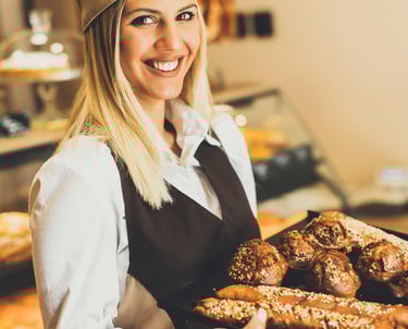 Femme debout qui tient un plateau  remplie de viennoiserie 
