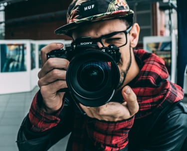 Un homme à lunette et casquette qui prend une photo