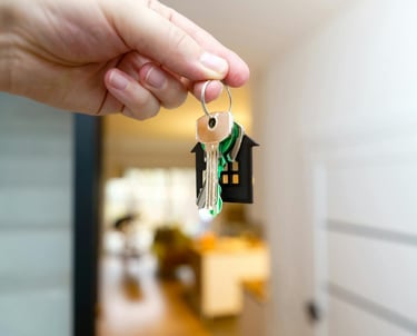 une personne tenant un porte-clés avec une clé de maison