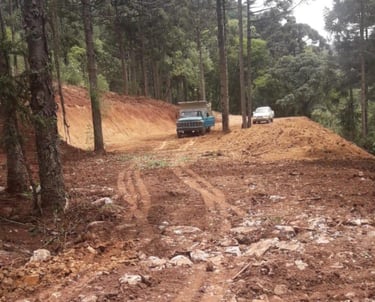 a truck driving down a dirt road with a truck in the background