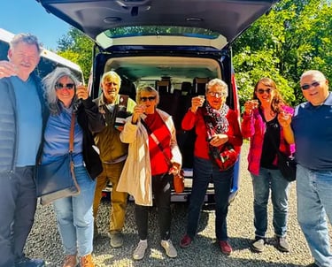 a group of people standing around a van smiling at the camera with drinks in their hands