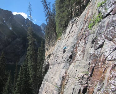 a person climbing a mountain side of a cliff