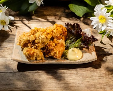 Crispy Japanese chicken karaage served with creamy mayo and lettuce on a rustic wooden table with white daisies.