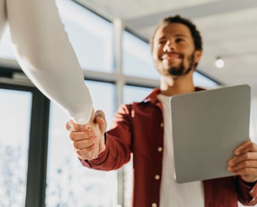 um homem e uma mulher apertando as mãos em uma reunião