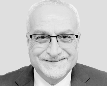 A picture of Dr. Burhan Ghanayem smiling and facing the camera wearing a suit