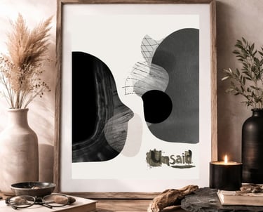 Framed monochromatic abstract wall art displayed on a rustic wooden table with a lit candle and pampas grass.