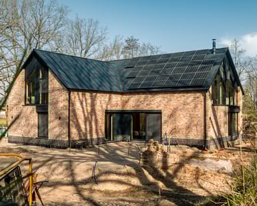 Modernes Einfamilienhaus mit Klinkerfassade, großen Glasflächen und Solarpaneelen auf dem Dach