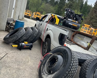 Mobile tire service truck with an air compressor and large school bus tires for roadside repair.