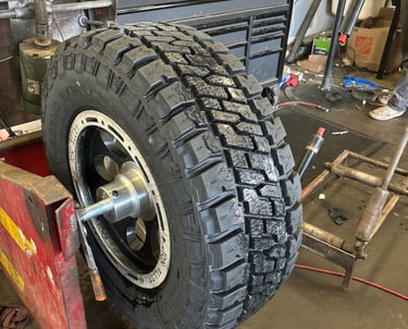 All-terrain truck tire mounted on a rim balancer in a professional automotive repair shop.