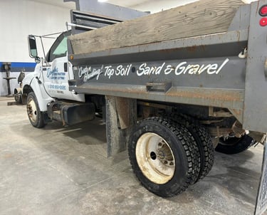White custom hauling dump truck for top soil, sand, and gravel parked in a commercial garage.