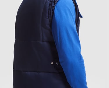 Imagen de un hombre que lleva una sudadera azul royal y un chaleco aolchado en color marino.
