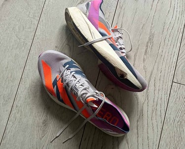 a pair of white adidas running shoes with pink and orange stripes