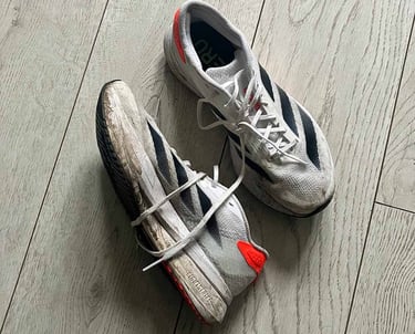 a pair of white adidas running shoes with black stripes