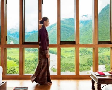 a Bhutanese woman standing in front of a large window at Como Uma Hotel in Punakha, Bhutan.