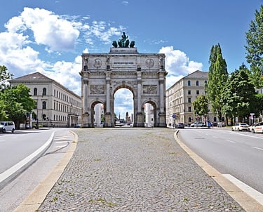 A large archway in a city street framing a clear blue sky.