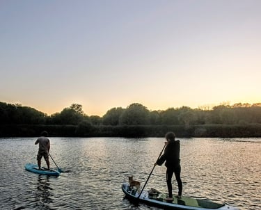 Dos personas remando sobre paddle surf al atardecer rio ulla