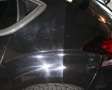 Carrosserie d'une voiture noire polie et lustrée, reflétant la lumière pour une finition miroir impe