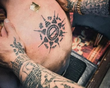 a man with traditional thai sak yant tattoos on his back holded by another man with sak yant tattoos