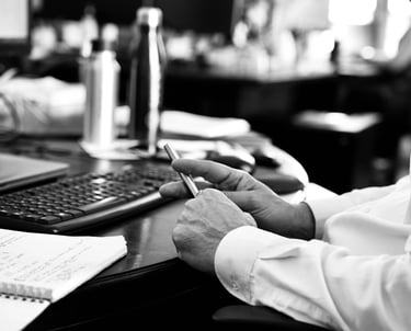 Mains d'un employé tenant un stylo devant l'ordinateur dans le bureau