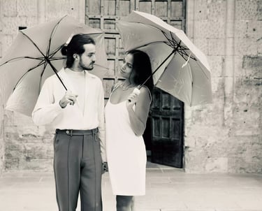 Séance d'un couple qui s'engage devant une église avec des parapluies