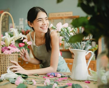A florist smiling and preparing a basket of flowers for a customer