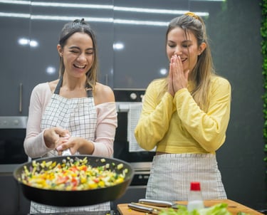 Two women making a meal in a pan and smiling