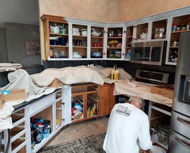 a man in white painting kitchen cabinets