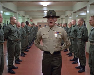 a man in uniform uniform standing in a room with other uniformed personnel