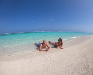 two women laying on the beach in front of a blue sky