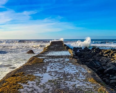 Oregon Coast - A pier jetty next to the lighthouse at a beach in Bandon