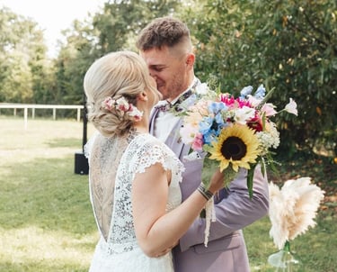 La mariée enlace le marié avec émotion lors de la découverte, bouquet coloré à la main.