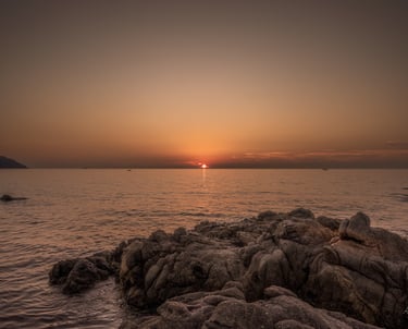 a sunset over the ocean with a boat in the distance