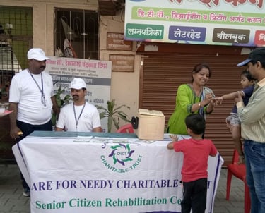 a group of men, woman, and children are standing in front of a table with a sign doing vaccination