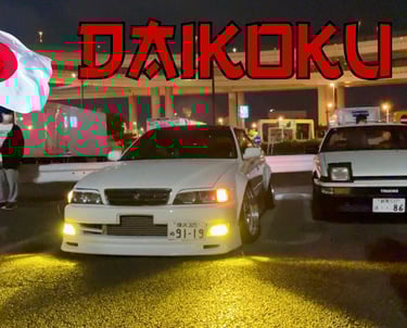 deux voitures en extérieur de nuit avec un drapeau japonais et le mot "Daikoku"