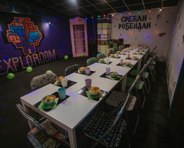 Svečano postavljen sto u party room-u igraonice Exploroom Niš, spreman za proslavu dečijeg rođendana ispod neonskog znaka "Sr