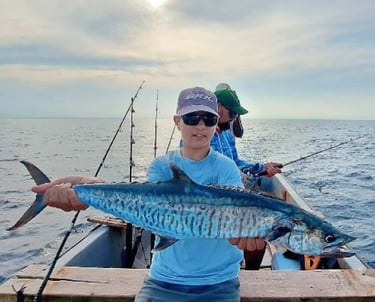 A happy beginner angler holding a fish on a boat in Zanzibar