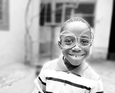 a young boy wearing home-made glasses and a striped shirt
