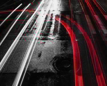 a black and white photo of a city street with red and white light streaks